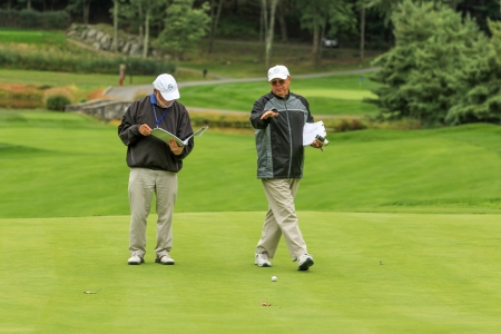 two officials looking at a green